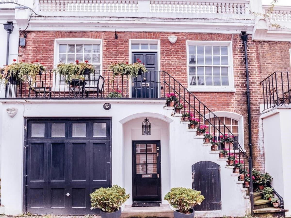 Red brick house with black painted doors, white window frames and railings
